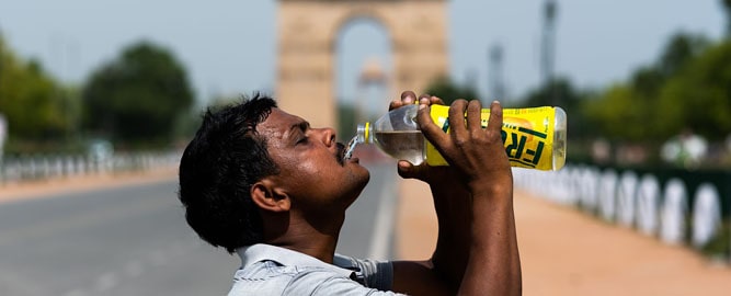 Man drinking water in front of India Gate, hot temperatures in Delhi
